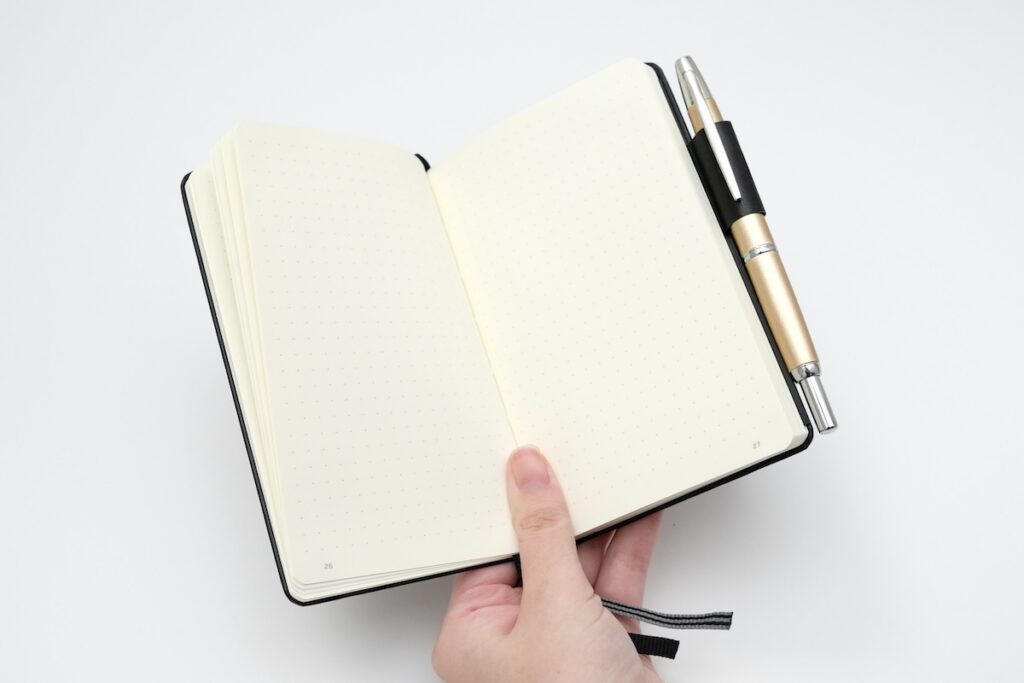 開いたノートを手に持っている様子