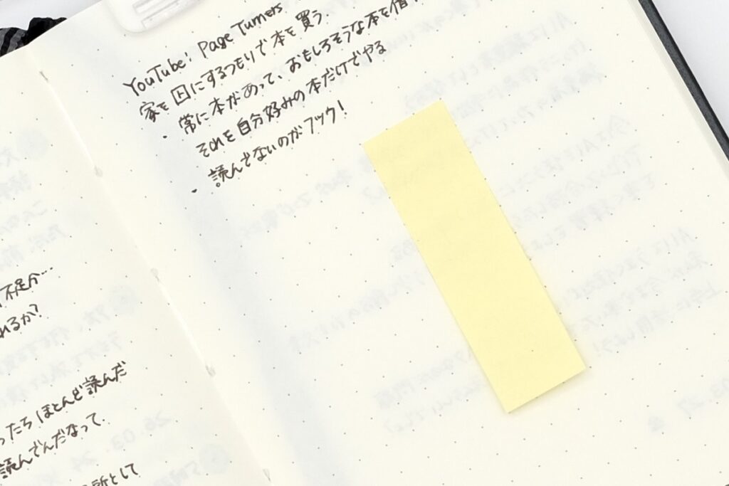 開いたモレスキンノートの中身アップ、付箋が貼ってあるところ
