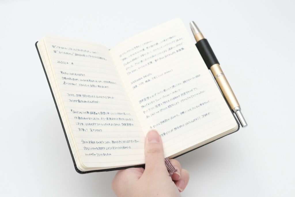 開いたノートを手で持っている様子